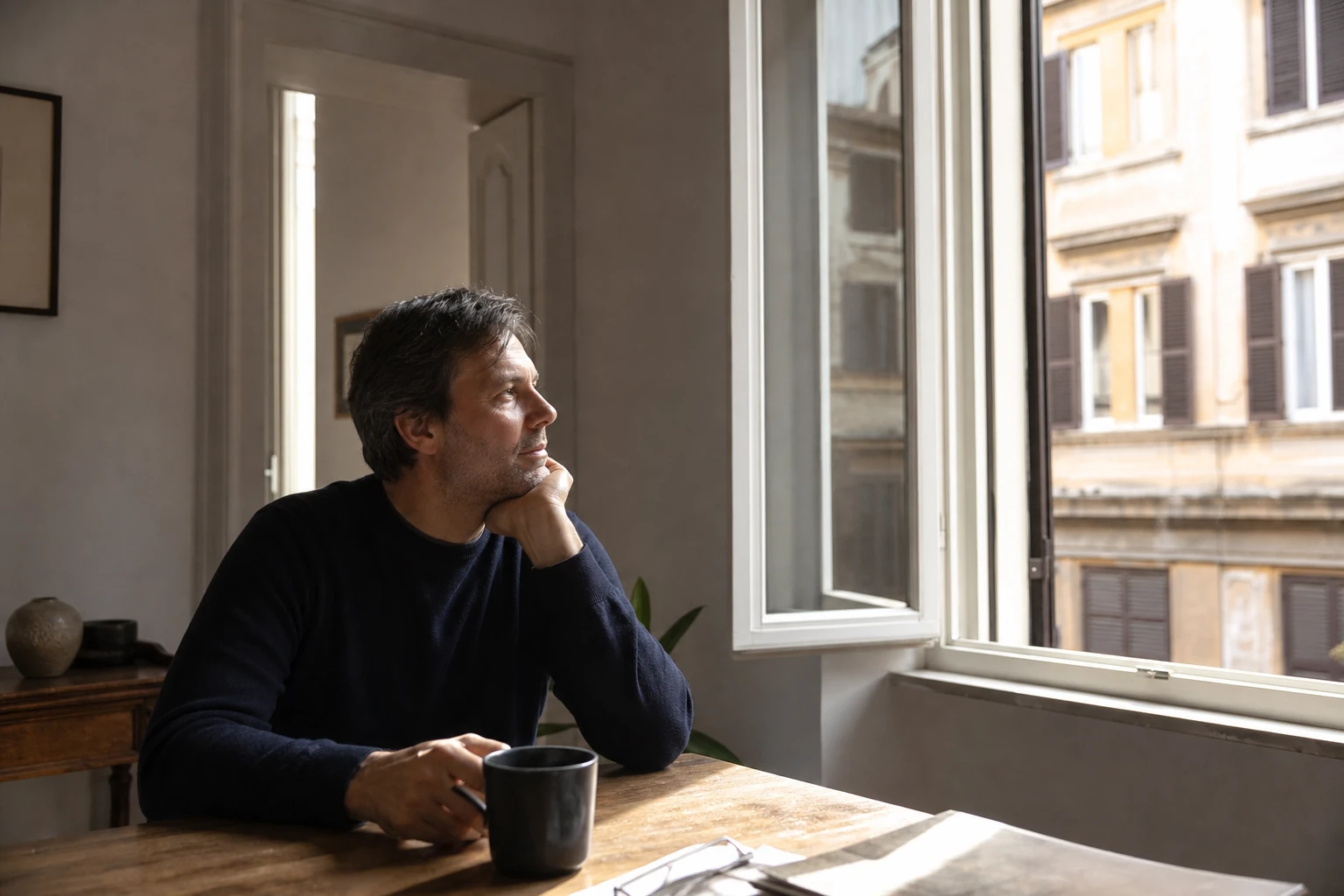 Persona seduta vicino a una finestra al mattino mentre ritrova calma ed energia.